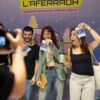 Tres persones posen amb les acreditacions davant del plafó de L'Aferrada, mentre algú les fotografia